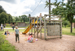 Børn leger på legeplads med rutchebane og klatrestativ i ferieparken Huttopia Calvados - Normandie, Frankrig.