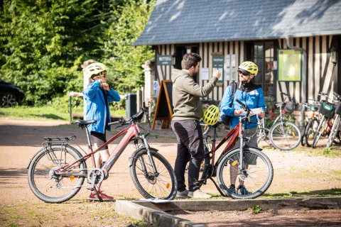 Huéspedes se preparan para un tour en bicicleta en Huttopia Calvados - Normandie con guía y cascos.