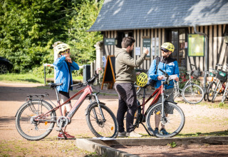 Gæster forbereder sig på cykeltur ved Huttopia Calvados - Normandie feriepark med guide og cykler.