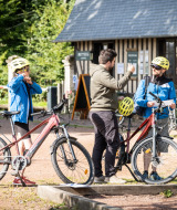 Huéspedes se preparan para un tour en bicicleta en Huttopia Calvados - Normandie con guía y cascos.