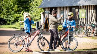 Huéspedes se preparan para un tour en bicicleta en Huttopia Calvados - Normandie con guía y cascos.