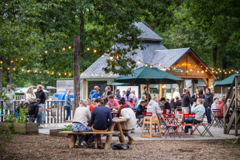 Mensen samen buiten onder sfeerverlichting bij Huttopia Lac de Sillé, Pays de la Loire, Frankrijk.