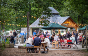 Persone che socializzano all'aperto sotto luci a catena a Huttopia Lac de Sillé, Pays de la Loire, Francia.