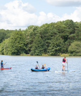 Personas practicando kayak y paddle surf en un lago cerca de Sillé-le-Guillaume, Pays de la Loire, Francia.