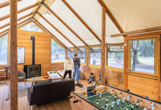 Intérieur chaleureux d’un lodge à Huttopia Lac de Sillé en France, avec familles et vue sur la forêt.