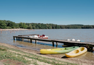 Lago vicino a Sillé-le-Guillaume, Pays de la Loire, Francia, con molo in legno, canoe e bagnanti.