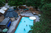Luftfoto af poolområde og spisested omgivet af skov hos Huttopia Lac de Sillé i Pays de la Loire, Frankrig.