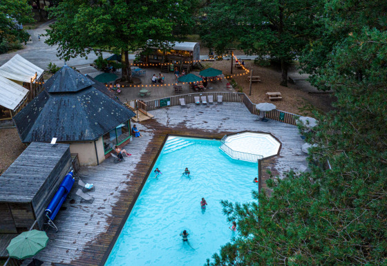 Luftfoto af poolområde og spisested omgivet af skov hos Huttopia Lac de Sillé i Pays de la Loire, Frankrig.