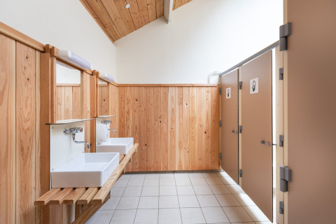 Modern toiletgebouw met houten panelen en wasbakken bij Huttopia Lac de Sillé in Frankrijk.
