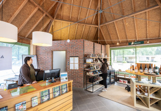 Reception and shop at Huttopia Lac de Sillé, showing two women and various local products on display.