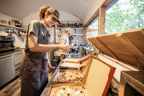 Twee medewerkers verpakken verse pizza’s in dozen in een keuken bij Huttopia Lac de Sillé, Frankrijk.