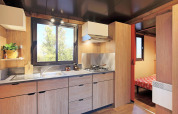 Cocina moderna dentro de una tienda safari en Huttopia Ars-en-Ré, Francia, con gabinetes de madera.