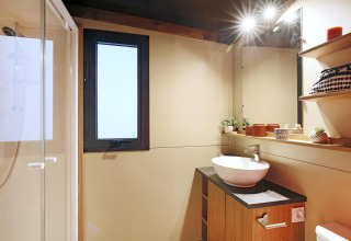 Baño moderno en la tienda safari Arizona de Huttopia Ars-en-Ré con ducha, lavabo y decoración cálida.