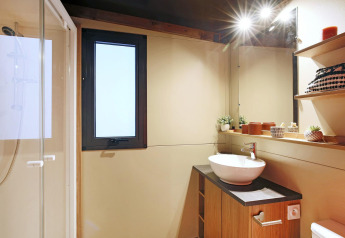 Baño moderno en la tienda safari Arizona de Huttopia Ars-en-Ré con ducha, lavabo y decoración cálida.