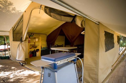 Intérieur d'une spacieuse tente Safari Classic à Huttopia Calvados - Normandie avec cuisine et table à manger.