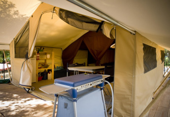 Intérieur d'une spacieuse tente Safari Classic à Huttopia Calvados - Normandie avec cuisine et table à manger.
