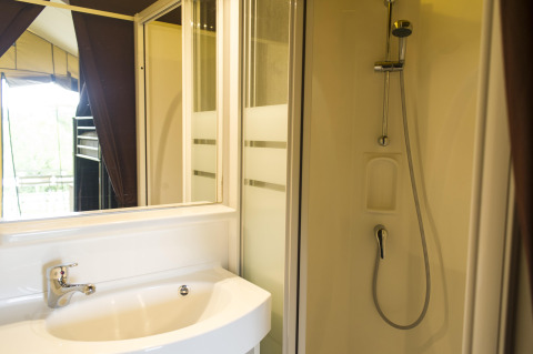 Badkamer met douche en wastafel in een safaritent bij Tent Sweet, Huttopia Calvados - Normandië, Frankrijk.
