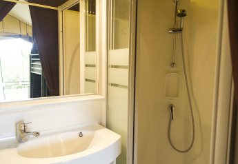 Badkamer met douche en lavabo in een safaritent bij Tent Sweet, Huttopia Calvados - Normandië, Frankrijk.
