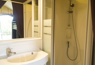 Bagno con doccia e lavandino in una tenda safari presso Tent Sweet, Huttopia Calvados - Normandie, Francia.