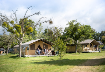 Safari telte ved Huttopia Calvados i Normandiet, Frankrig, med mennesker siddende udenfor på en solrig dag.