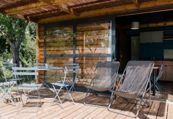 Outdoor terrace of Chalet Evasion at Huttopia Calvados - Normandie with tables, chairs, and loungers.