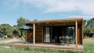 Chalet Portland set udefra, med terrasse, havemøbler, parasol og omkringliggende grønne områder.