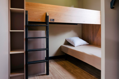 Zimmer mit Etagenbett und Regalen im Chalet Portland bei Huttopia Calvados - Normandie, Frankreich.