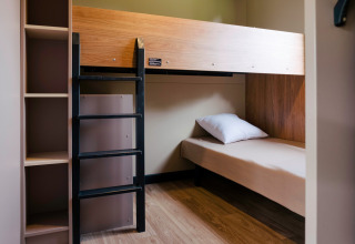 Zimmer mit Etagenbett und Regalen im Chalet Portland bei Huttopia Calvados - Normandie, Frankreich.