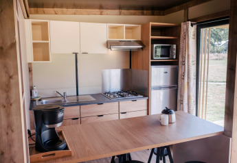 Moderne køkken i Chalet Portland, Huttopia Calvados - Normandie, med komfur, køleskab og kaffemaskine.