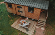 Vista aérea de una cabaña Roulotte de madera con terraza en Huttopia Calvados, Normandía, Francia, y dos personas comiendo.