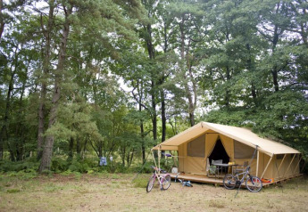 Tienda safari Toile & Bois Classic en Huttopia Lac de Sillé, Francia, rodeada de bosque y bicicletas fuera.