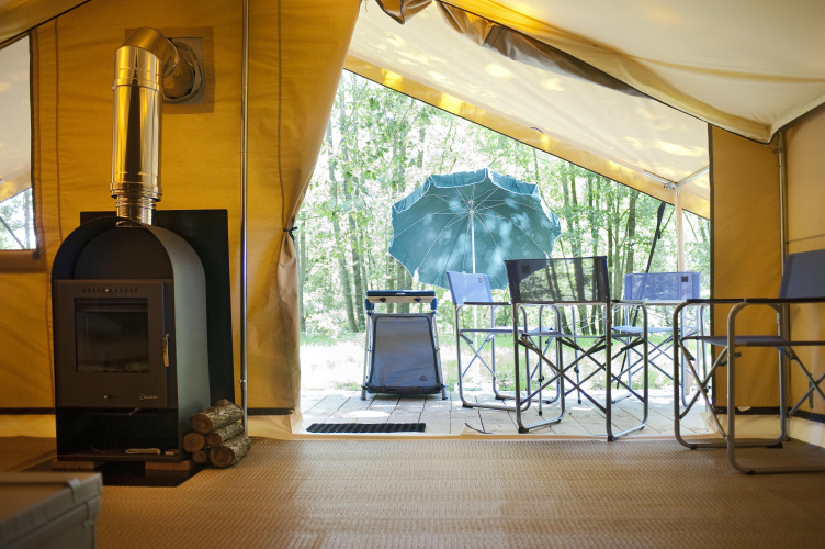 Blick aus dem Safari-Zelt Bungalow Trappeur poêle bei Huttopia Lac de Sillé, mit Terrasse und Holzofen.