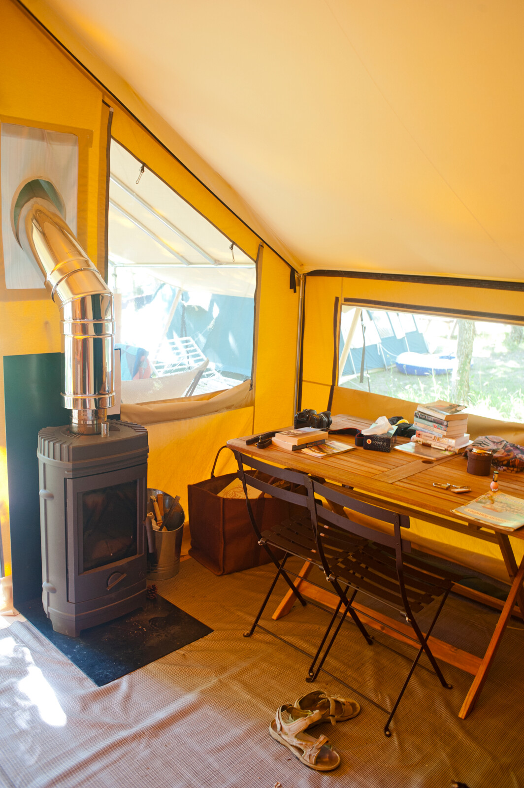 Interieur van safaritent met houtkachel en tafel, Bungalow tent Trappeur poêle bij Huttopia Lac de Sillé, Frankrijk.