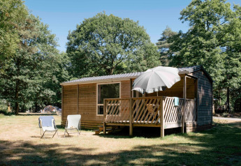 Casa móvil Cottage en Huttopia Lac de Sillé, Francia, con terraza, sombrilla y vistas al bosque.