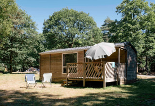 Mobilheim Cottage bei Huttopia Lac de Sillé in Frankreich mit Terrasse, Sonnenschirm und Wald.