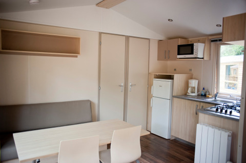 Interieur van Mobile home Cottage bij Huttopia Lac de Sillé in Frankrijk, met keuken en eethoek.