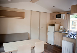 Vista interior de la Mobile home Cottage en Huttopia Lac de Sillé, Francia, con cocina y comedor pequeños.