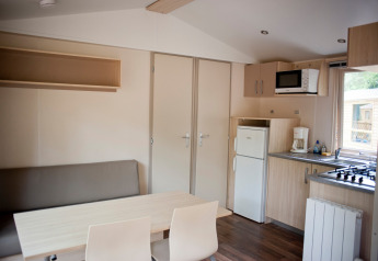 Vista interior de la Mobile home Cottage en Huttopia Lac de Sillé, Francia, con cocina y comedor pequeños.