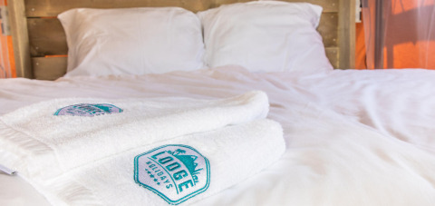 Cama de la tienda safari Base Lodge con toallas blancas en Boutique Camping Heart of Nature en Croacia.