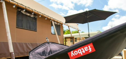 Tienda safari Base Lodge en Boutique Camping Heart of Nature en Croacia, con cielo soleado y sombrilla negra.