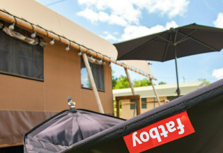 Tienda safari Base Lodge en Boutique Camping Heart of Nature en Croacia, con cielo soleado y sombrilla negra.