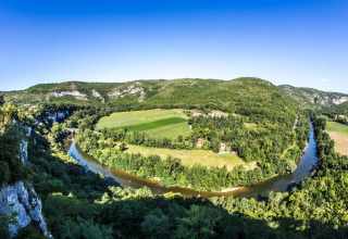 Panoramabillede af frodige grønne marker og en bugtende flod set fra Camping Les 3 Cantons i Occitanie, Frankrig.