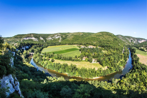 Vista panoramica di campi verdi e un fiume sinuoso da Camping Les 3 Cantons, Occitania, Francia.