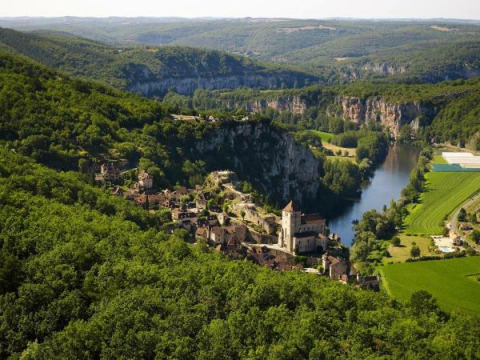 Vue aérienne du Camping Les 3 Cantons, parc de vacances en Occitanie, France, entouré de forêt et de rivière.