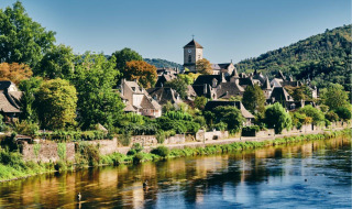 Foto van een charmant vakantiepark met glampingverblijven aan een rivier, omgeven door groene heuvels.
