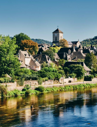 Foto de un parque vacacional pintoresco con alojamientos glamping junto a un río y colinas verdes alrededor.