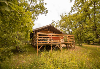 Safari Lodge-telt på Camping Les 3 Cantons i Frankrig, omgivet af frodig skov og grønne træer.
