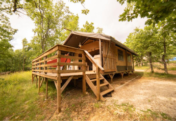Safari Lodge tent op Camping Les 3 Cantons in Frankrijk, tussen bomen en natuur, met houten terras.