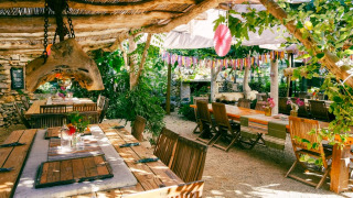 Buiten eetgedeelte bij Camping Les 3 Cantons in Occitanië, Frankrijk, met houten tafels en groene planten.