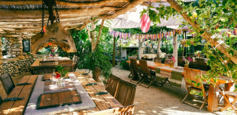 Zona de comedor al aire libre en Camping Les 3 Cantons, Occitanie, Francia, con mesas rústicas y plantas.